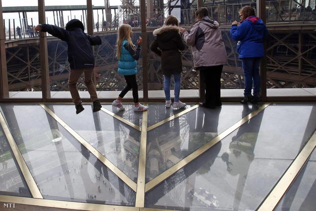 A párizsi Eiffel-torony felújított első szintjének új üvegpadlóján állnak látogatók