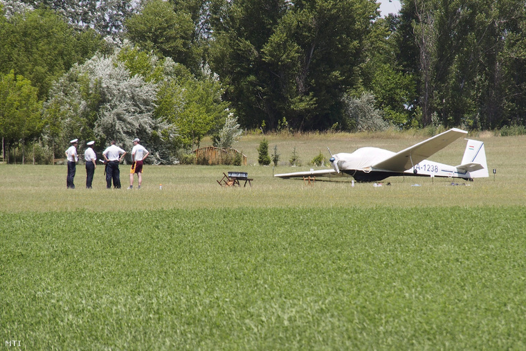 Rendőrök helyszínelnek a pusztaszeri repülőtéren 2014. július 2-án egy kisrepülőgép mellett amely manőver közben elsodort egy 18 éves nőt.