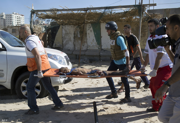 Mentőcsapatok egy halott fiút szállítanak el a gázai strandról 2014. júlus 16-án. Szerdán több mint húszan haltak meg az izraeli légicsapásokban.