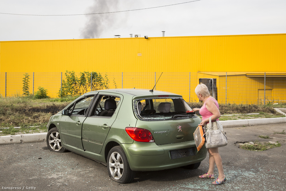 A harcoktól megviselt autóját vizsgálja egy donyecki nő. Egyelőre felbecsülhetetlen, hogy mennyi kárt okozott a kelet-ukrán konfliktus, ám az ország GDP-je már legalább öt százalékkal csökkent tavalyhoz képest. 