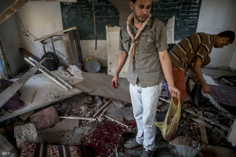 Palesztin férfiak kutatnak a romok között a találatot kapott ENSZ-iskola egyik termében