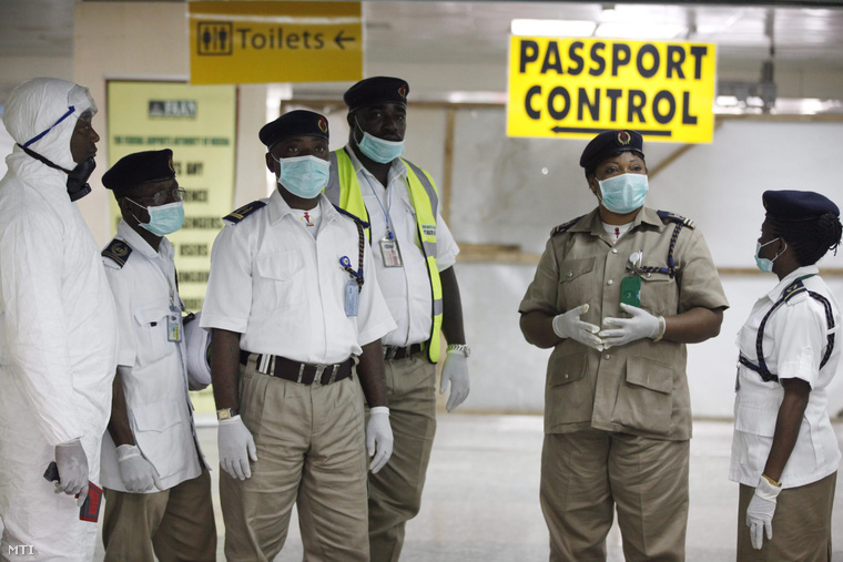A nigériai egészségügyi hatóság képviselői az érkező utasok megvizsgálására készülnek a lagosi Murtala Muhammed Nemzetközi Repülőtéren 2014. augusztus 4-én.