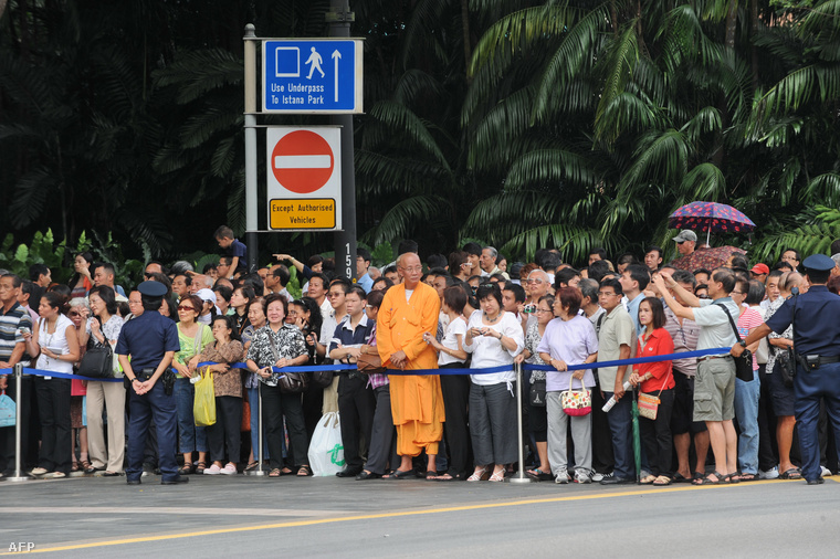 Katonai temetést figyelnek a járókelők egy szingapúri utcán