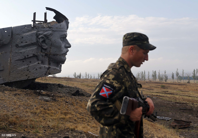 Oroszbarát fegyveres egy, a harcokban megrongálódott háborús emlékműnél, Savur-Mohyla hegy közelében, 2014. augusztus 28-án.