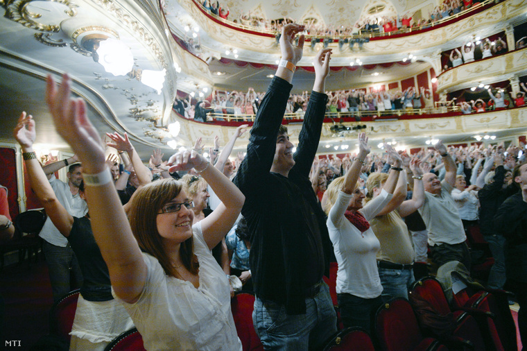 A nézők magasba emelik karjukat Eszenyi Enikő igazgató instruálására 2013. május 4-én a budapesti Vígszínházban ahol a Színházak éjszakáján a nézők bevonásával tartották meg a teátrum Csárdáskirálynő című korábbi darabjának próbáját.