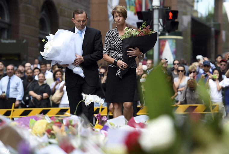 Tony Abbott ausztrál miniszterelnök és felesége Margie virágot helyez el annak a sydney-i kávézónak a közelében 2014. december 16-án ahol az előző napon tűzpárbaj alakult ki egy túszokat ejtő fegyveres férfi és rendőrök között.
