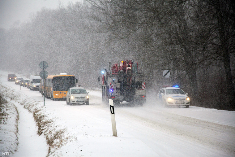 Rendőr irányítja a forgalmat a 61-es út bagolai emelkedőjénél Nagykanizsa közelében 2015. február 6-án ahol kamionok akadtak el a sűrű hóesésben és torlódik a forgalom.