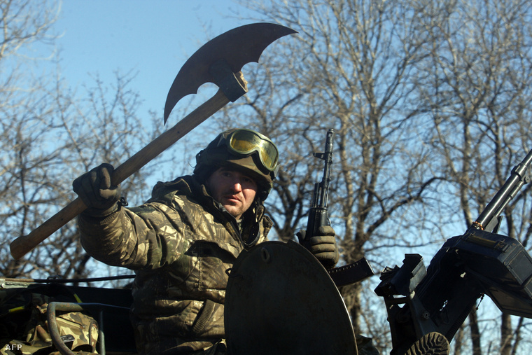 Egy ukrán katona csatabárddal a kezében ül egy csapatszállító tetején