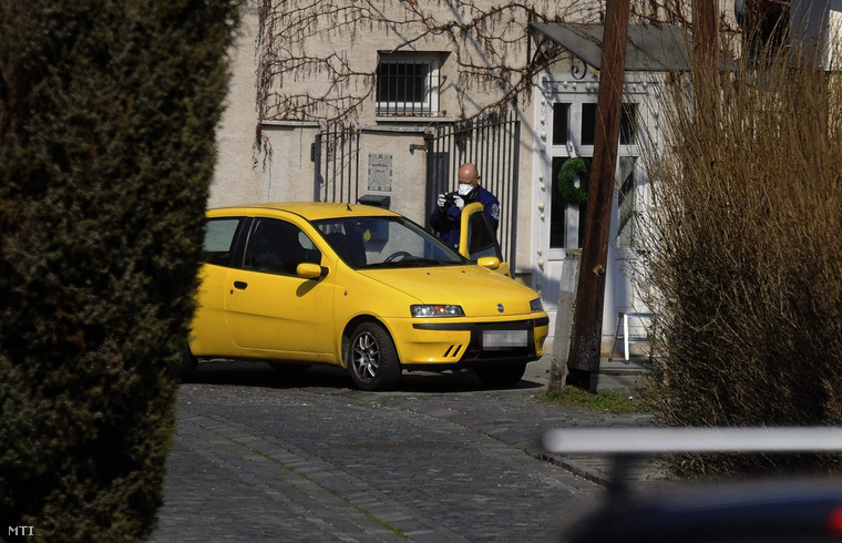 Rendőr áll egy gépkocsinál Szentendrén ahol holtan találtak egy 42 éves nőt otthonában 2015. március 20-ára virradóra.