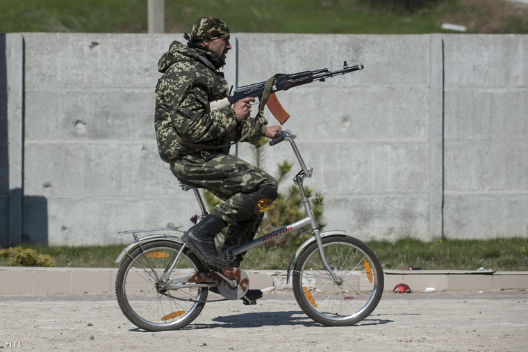 Ukrán katona kerékpározik a Mariupoltól keletre fekvő Sirokine településen Kelet-Ukrajnában 2015. április 15-én.