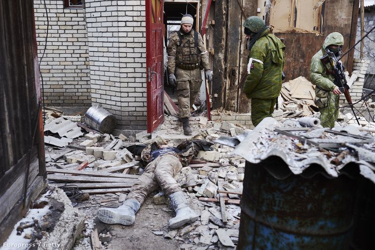 Oroszpárti szeparatisták egy lerombolt házban, egy ukrán katona holtteste mellett